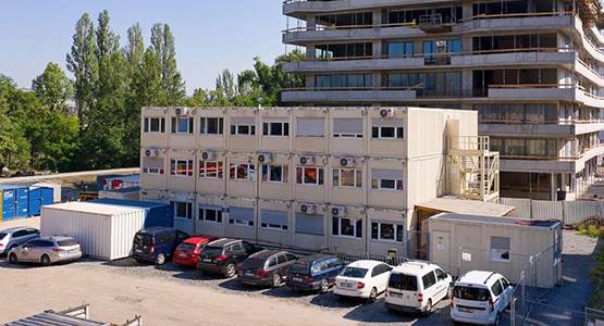 Několik stavebních buněk tvořící jednu velkou vícepodlažní kontejnerovou stavbu na míru.